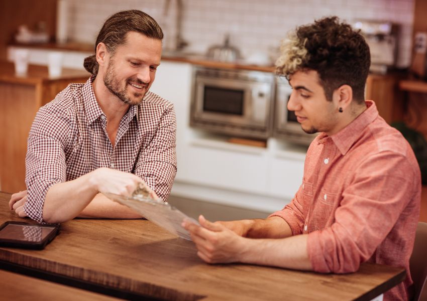 A landlord wiht a beard smiles as they screen a tenant for their rental unit.